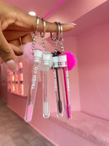 Group shot of Brush & GO keychain spoolies – travel lash brushes in white, black, and pink from Trish Co